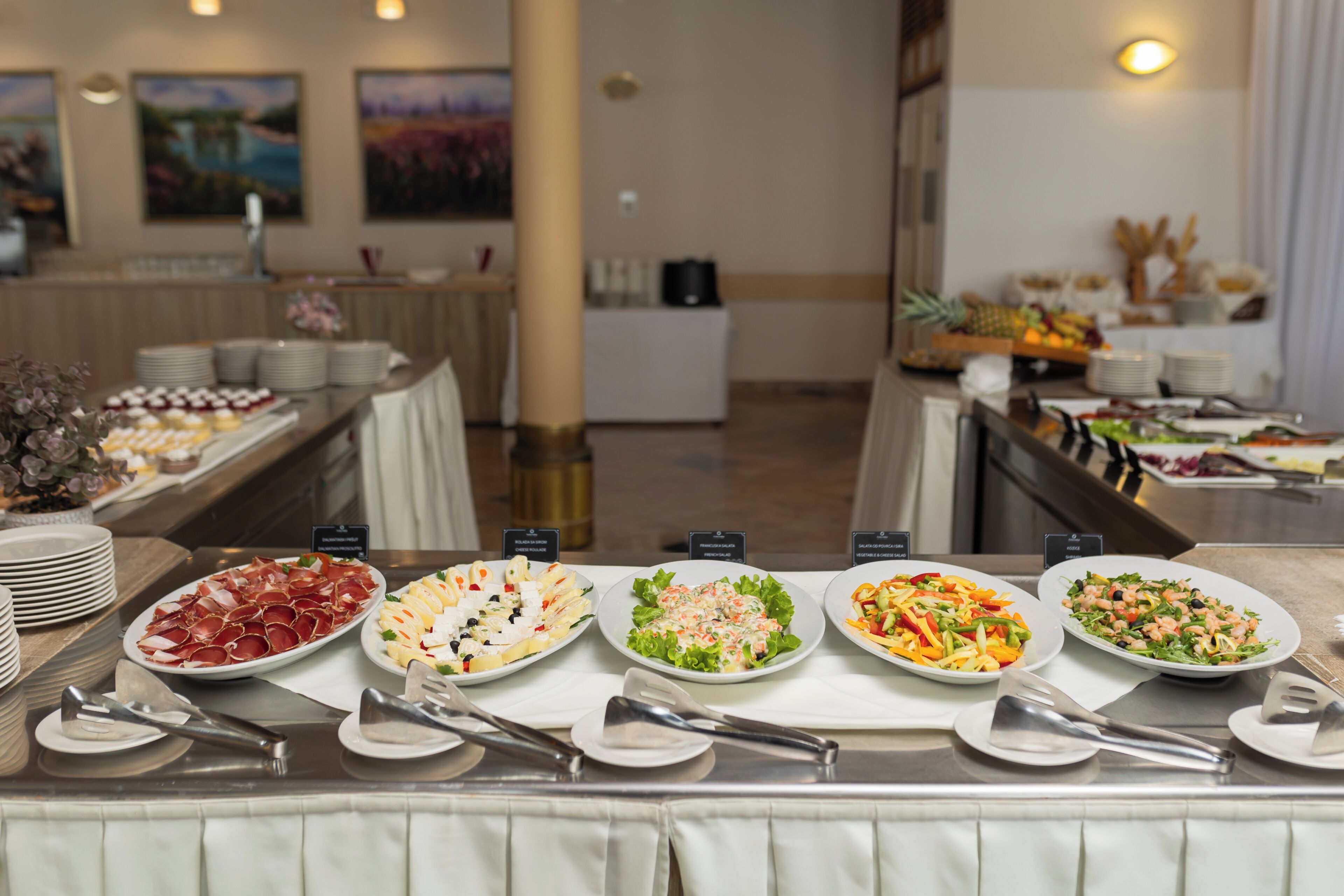 Un buffet con diversi piatti, tra cui insalate e carni, disposti su un tavolo con piatti e posate.