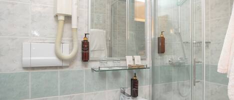 Un baño con cabina de ducha de vidrio, un lavabo blanco y un espejo.
