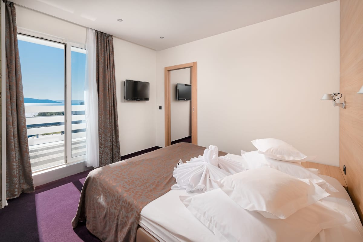Ein Hotelzimmer mit Bett, Fernseher, Holztür und Meerblick.