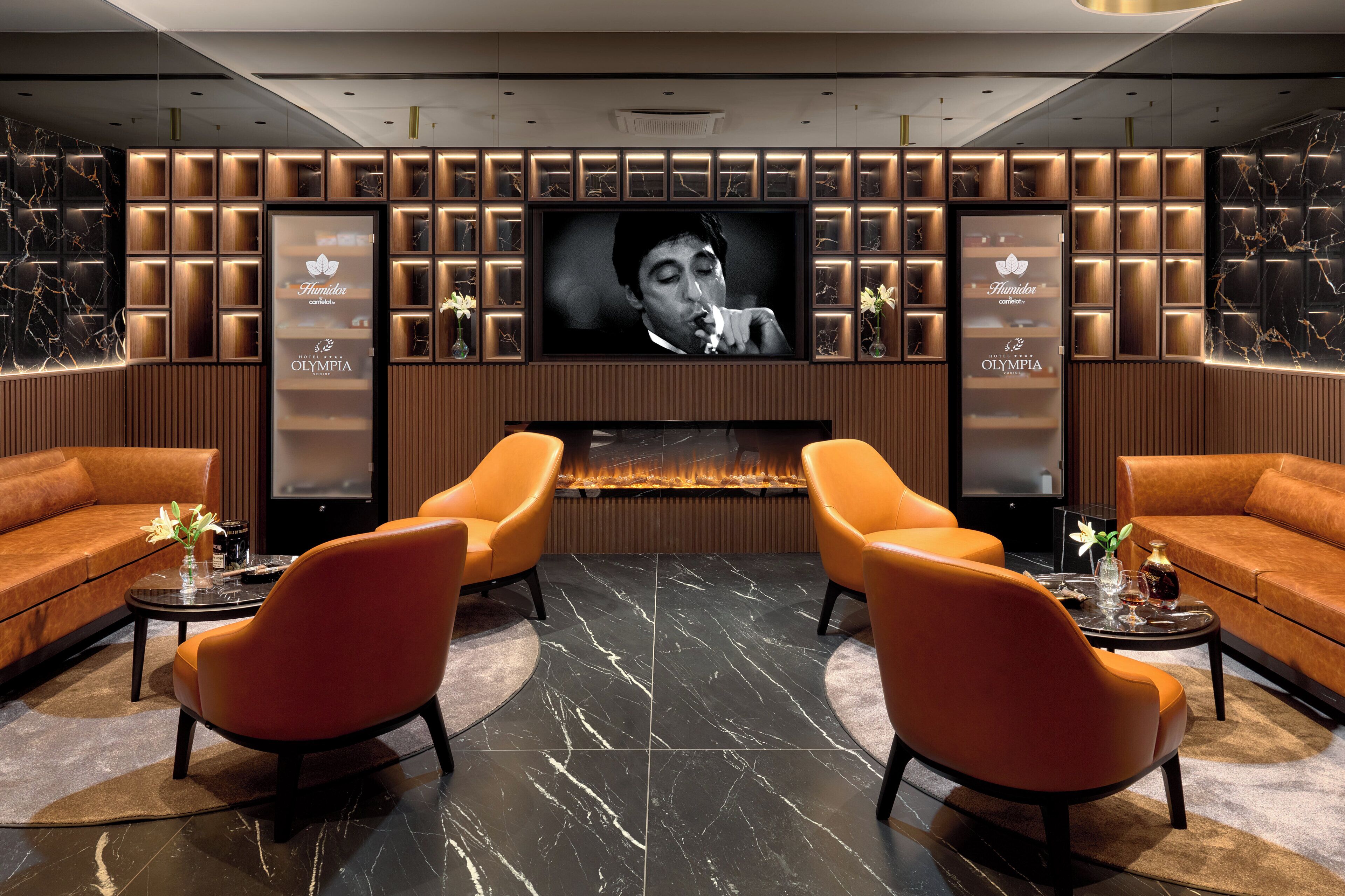 A modern lounge area with a large flat-screen TV, comfortable seating, and a built-in fireplace.