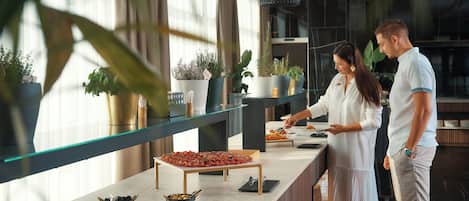 A buffet setup with various food items and potted plants.