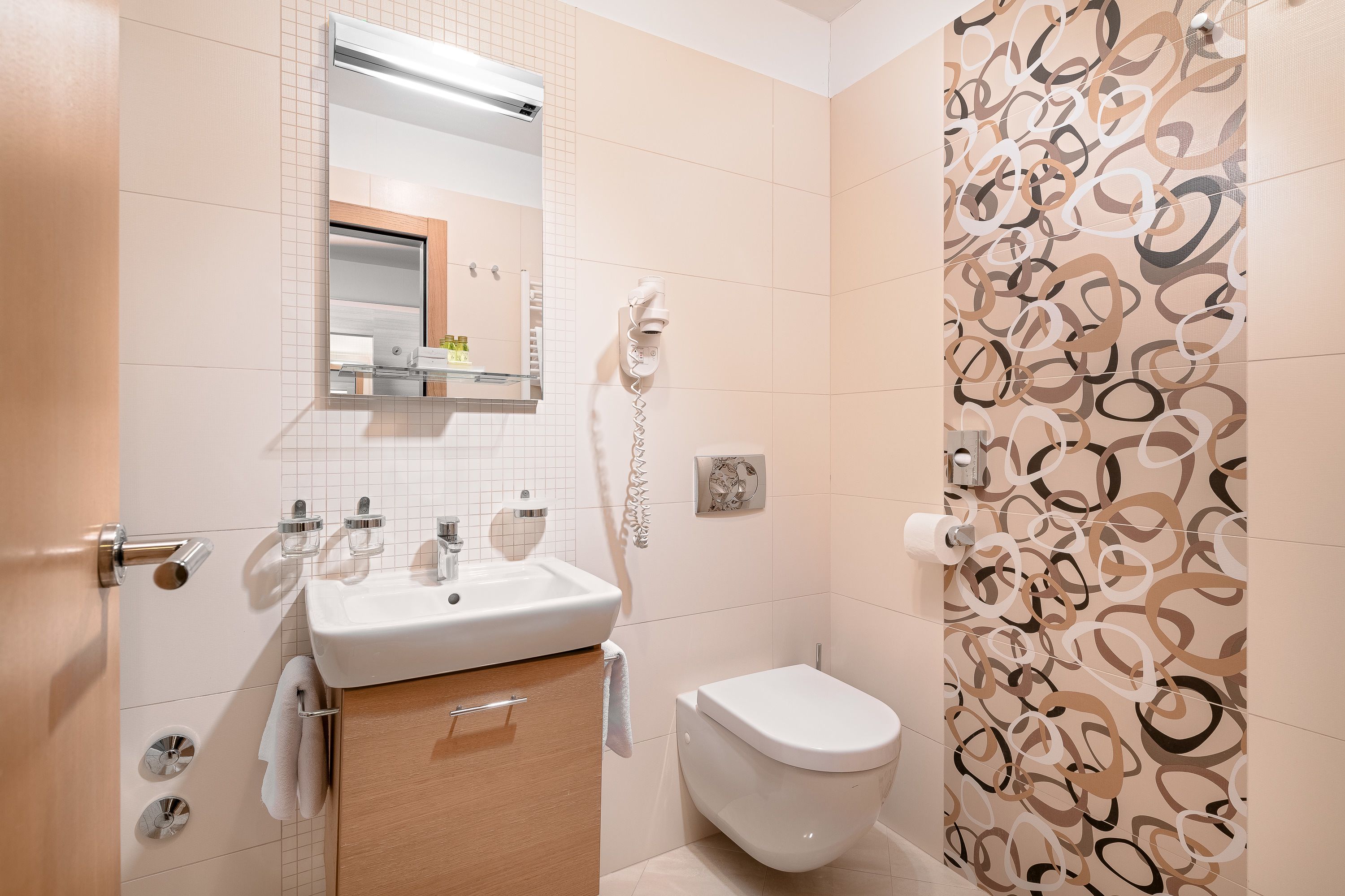 A bathroom with a sink, mirror, toilet, and a shower area.