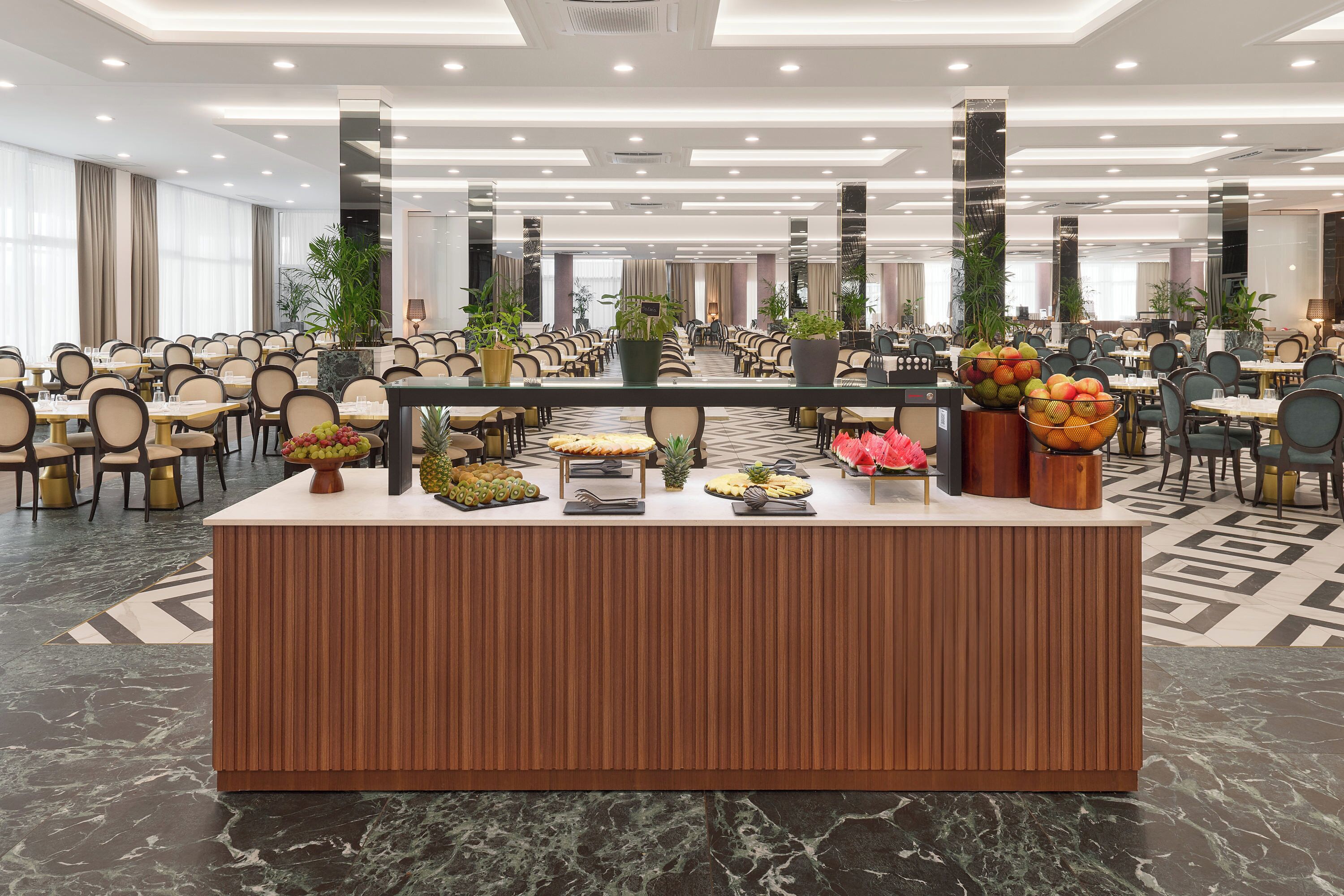 A buffet area with a marble floor, a wooden reception desk, and various food displays.