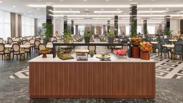 A buffet area with a marble floor, a wooden reception desk, and various food displays.