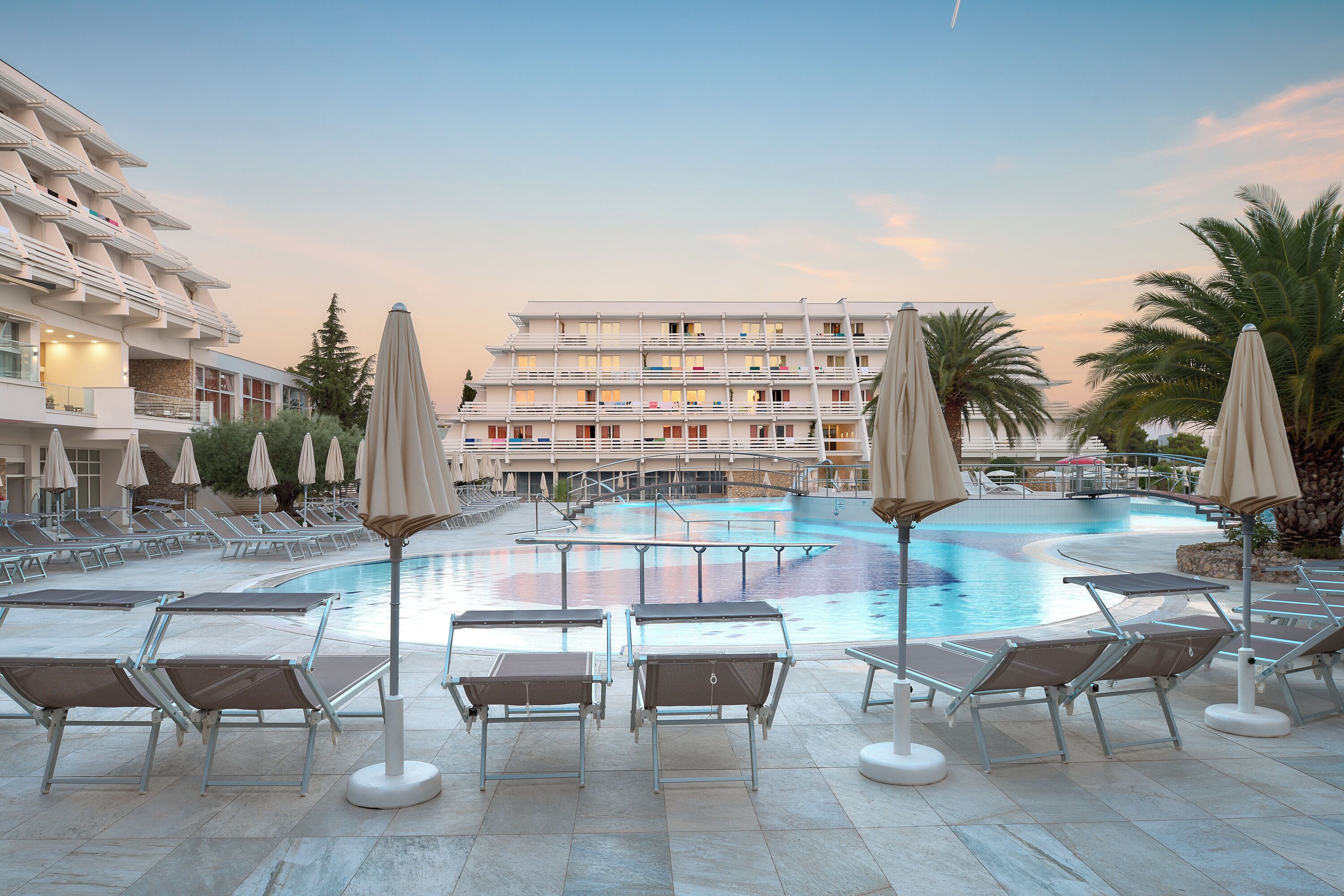 Un hotel con piscina, tumbonas y sombrillas.