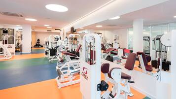 A gym with various exercise machines, a mirror wall, and a colorful floor.