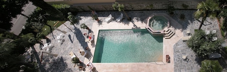 Una piscina al aire libre, sombrillas, sillones reclinables de piscina