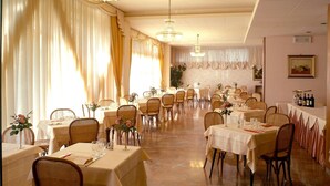 Un restaurant doté de nombreuses tables, de lustres et de rideaux élégamment drapés.