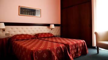 Une chambre d’hôtel avec un grand lit, deux tables de chevet avec des lampes, une porte en bois et un tableau encadré au mur.
