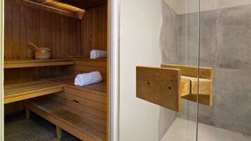 Una sauna con bancos de madera y una puerta de cristal.