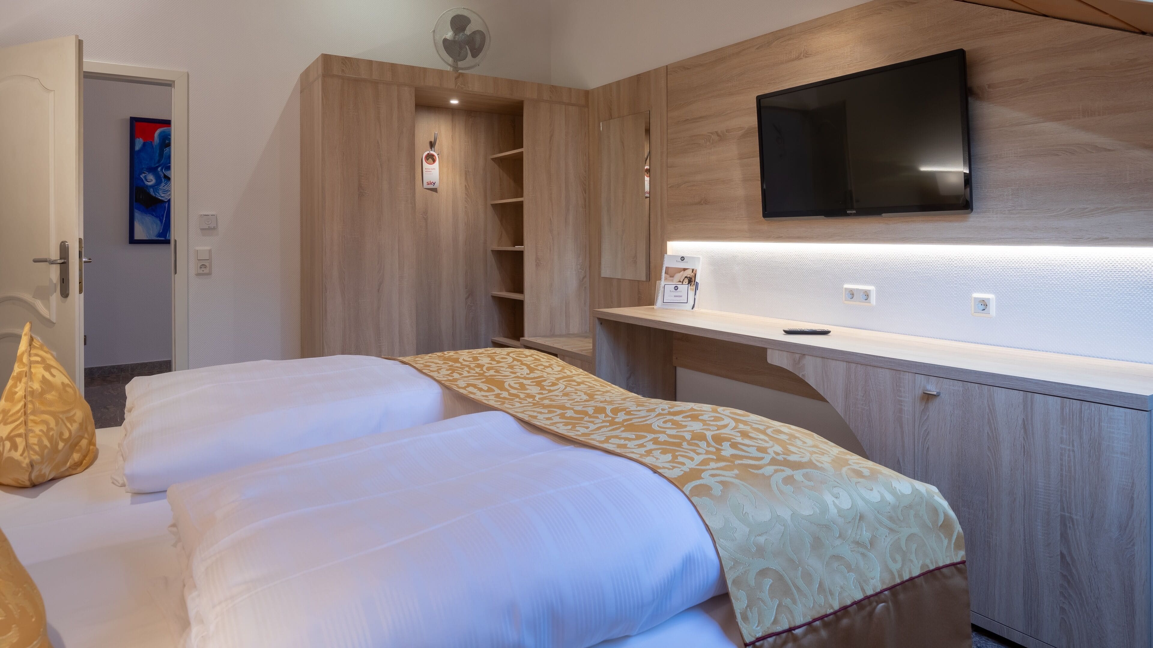 Ett hotellrum med en säng, ett skrivbord, en tv och en garderob.