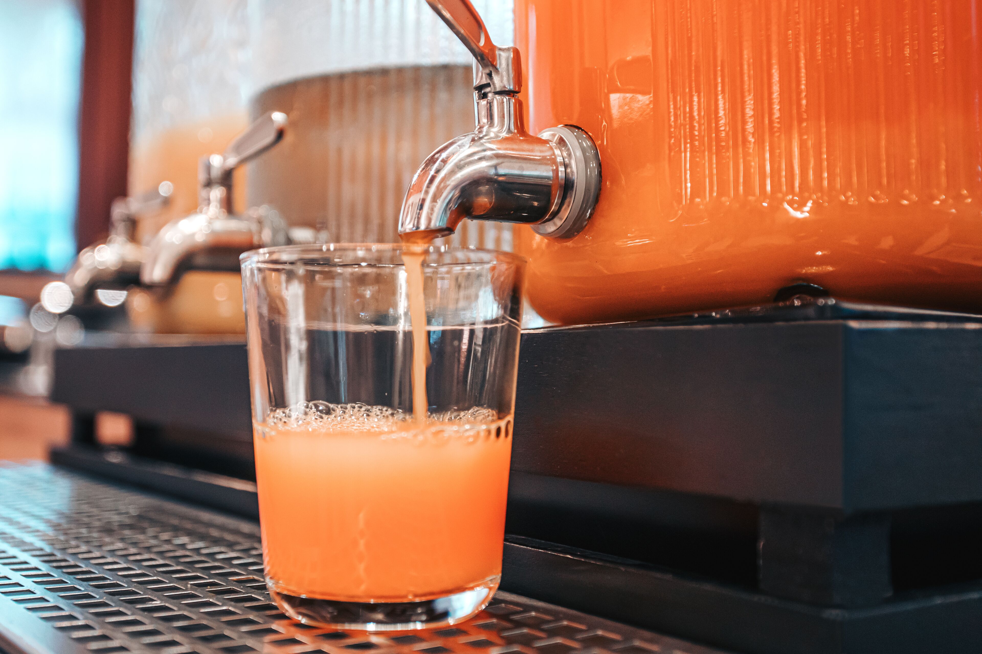 Un vaso de jugo de naranja siendo servido desde una máquina de café.