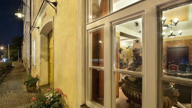 A building with large windows, a door, and a potted plant on the sidewalk. - EA Hotel Jelení dvůr Prague Castle (Prague)