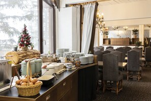 Una barra de desayuno con un árbol de Navidad, zona de comedor con sillas y un espejo grande.