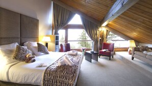A bedroom with a large bed, a red armchair, a sofa, and a small table. - Odalys Hotel New Solarium (Courchevel)