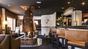 A modern bar area with leather chairs, a large copper sculpture, and a Christmas tree. - Odalys Hotel New Solarium (Courchevel)