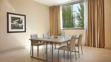 Un comedor con una mesa preparada para seis personas, un cuadro en la pared y una ventana con cortinas.