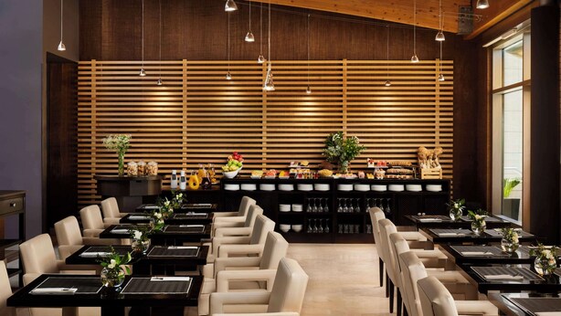 A restaurant with a wooden ceiling and slatted wall design, featuring multiple dining tables and chairs. - NH Alcorcón (Alcorcon)