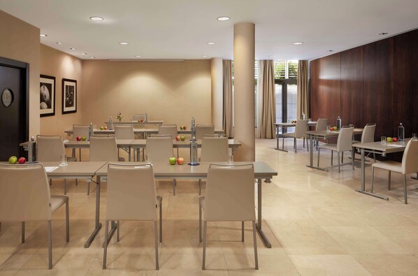 A hotel dining area with multiple tables and chairs, a clock on the wall, and framed pictures. - NH Alcorcón (Alcorcon)