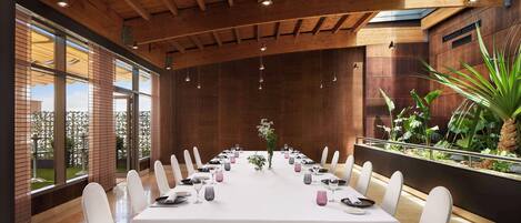 Un salón de conferencias con una larga mesa, sillas blancas y un techo de madera.