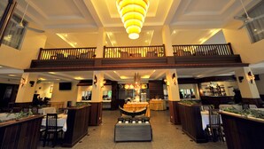 A spacious hotel lobby with a central chandelier, multiple dining areas, and a balcony overlooking the interior. - City River Hotel (Siem Reap)