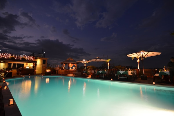 Alberca al aire libre, sombrillas en la alberca y camastros