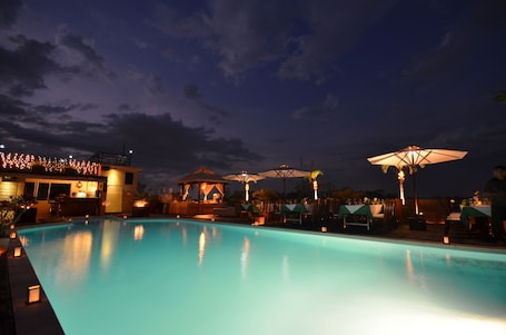 Una piscina al aire libre, sombrillas, sillones reclinables de piscina