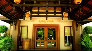 A traditional wooden entrance with glass doors, potted plants, and hanging lanterns. - City River Hotel (Siem Reap)