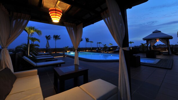 An outdoor pool area with lounge chairs and a hot tub, surrounded by palm trees and a gazebo. - City River Hotel (Siem Reap)