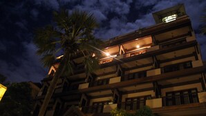 A multi-story building with balconies and a palm tree in front. - City River Hotel (Siem Reap)
