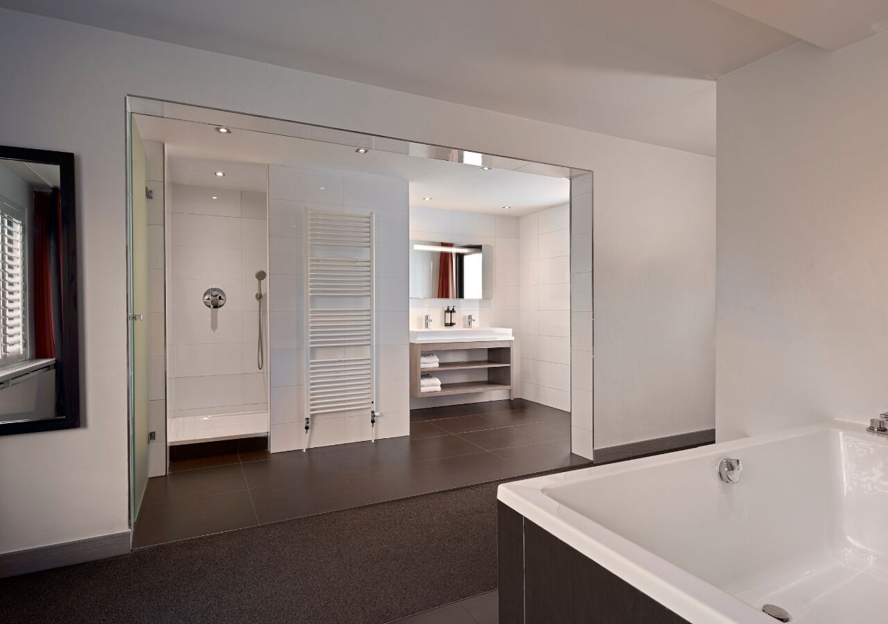 Ein modernes Badezimmer mit einer großen Badewanne, einer begehbaren Dusche und einem Waschtisch mit Spiegel.