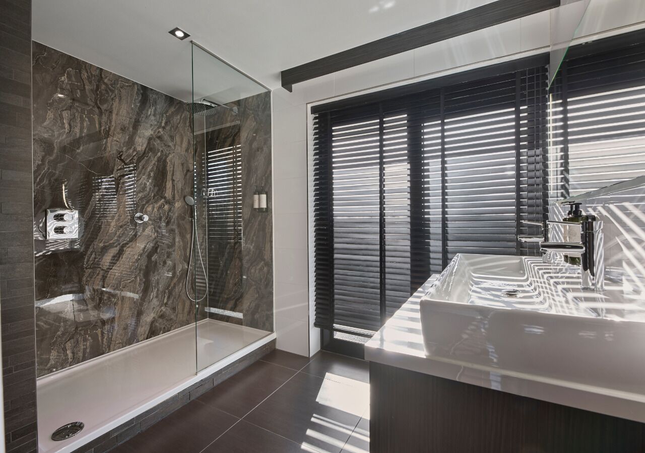 A modern bathroom with a glass-enclosed shower, a large bathtub, and a vanity with a mirror.