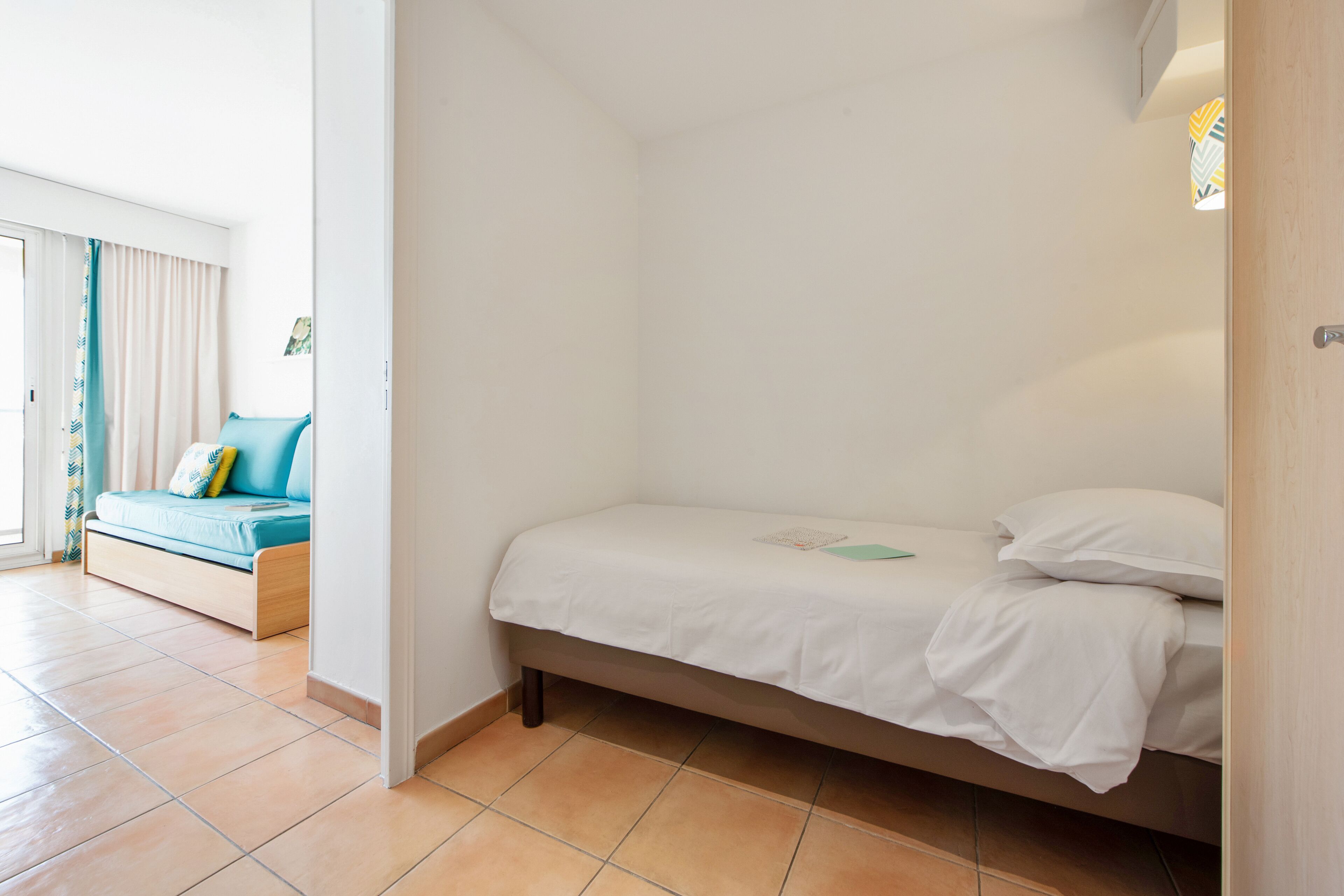 A bedroom with a bed, a sofa, and a window.
