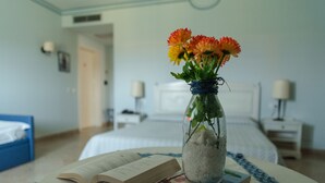 A hotel room with a bed, bedside tables, a lamp, a book, and a vase with flowers on a table. - Relais Antiche Saline (Paceco)