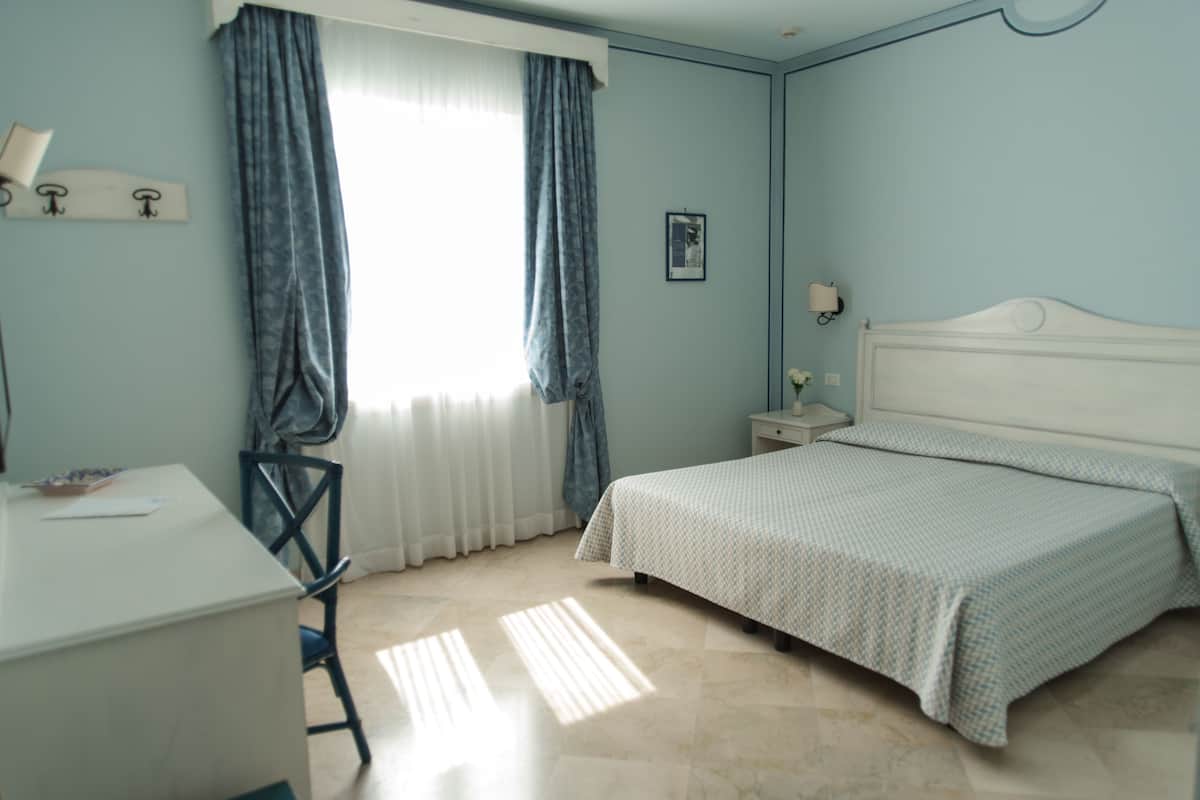 A room with a bed, a desk, and a chair.