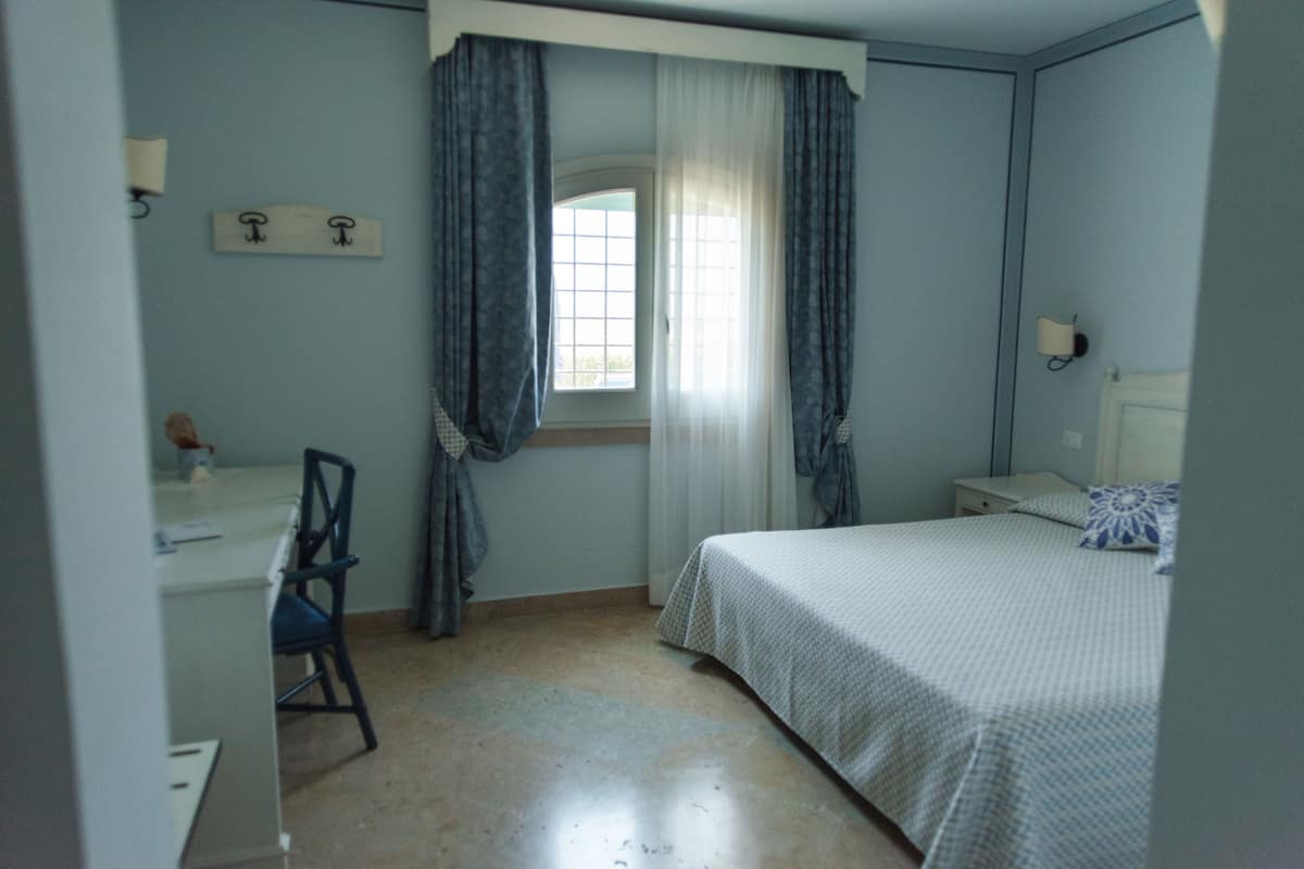 A bedroom with a bed, a desk, and a chair.