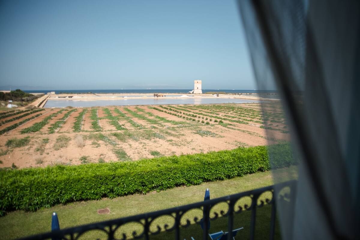 A coastal landscape with a tower, fields, and a body of water.