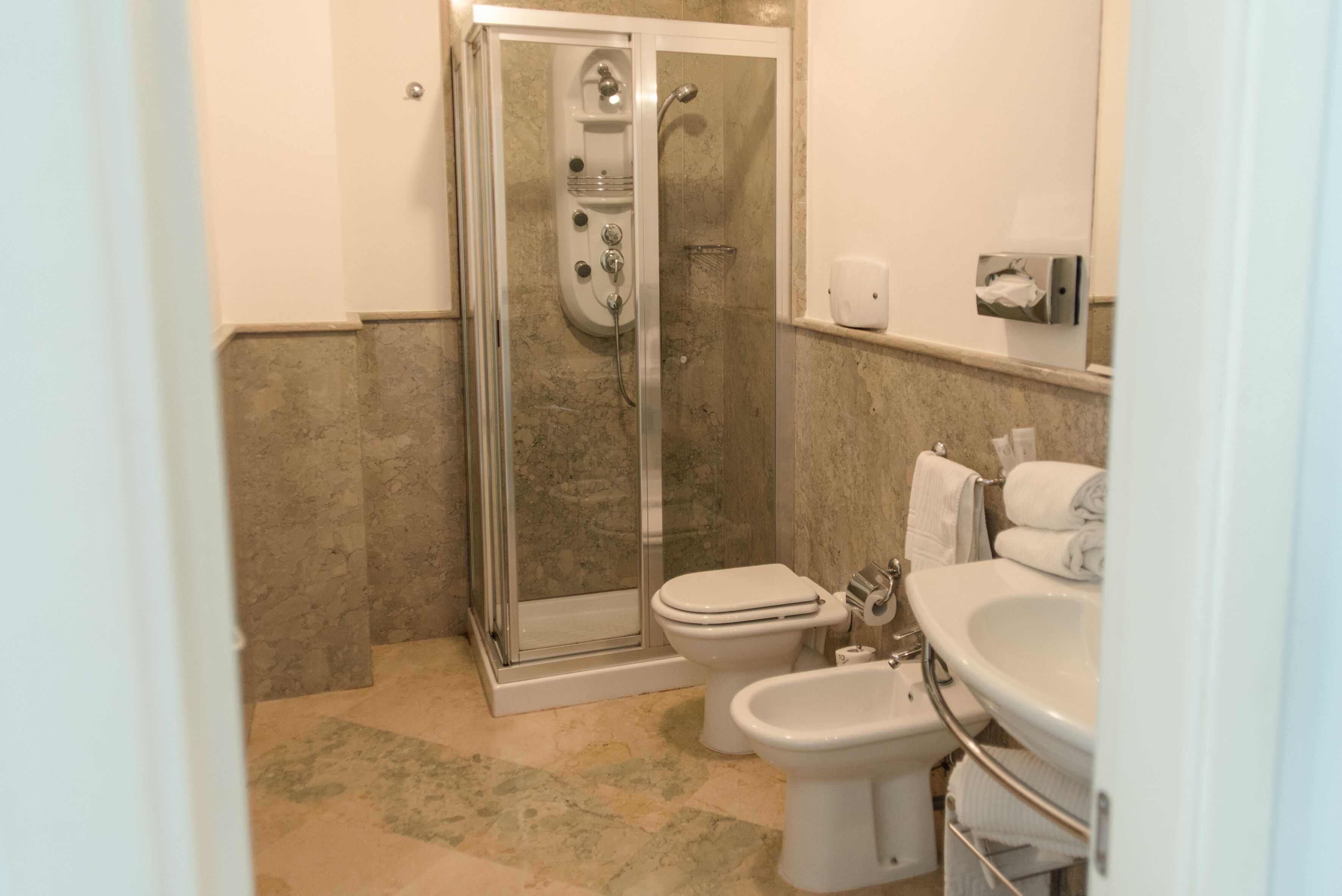 Un bagno con doccia vetro, water e lavabo.