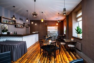 Un restaurante con suelo de madera, sillas negras e iluminación colgante.
