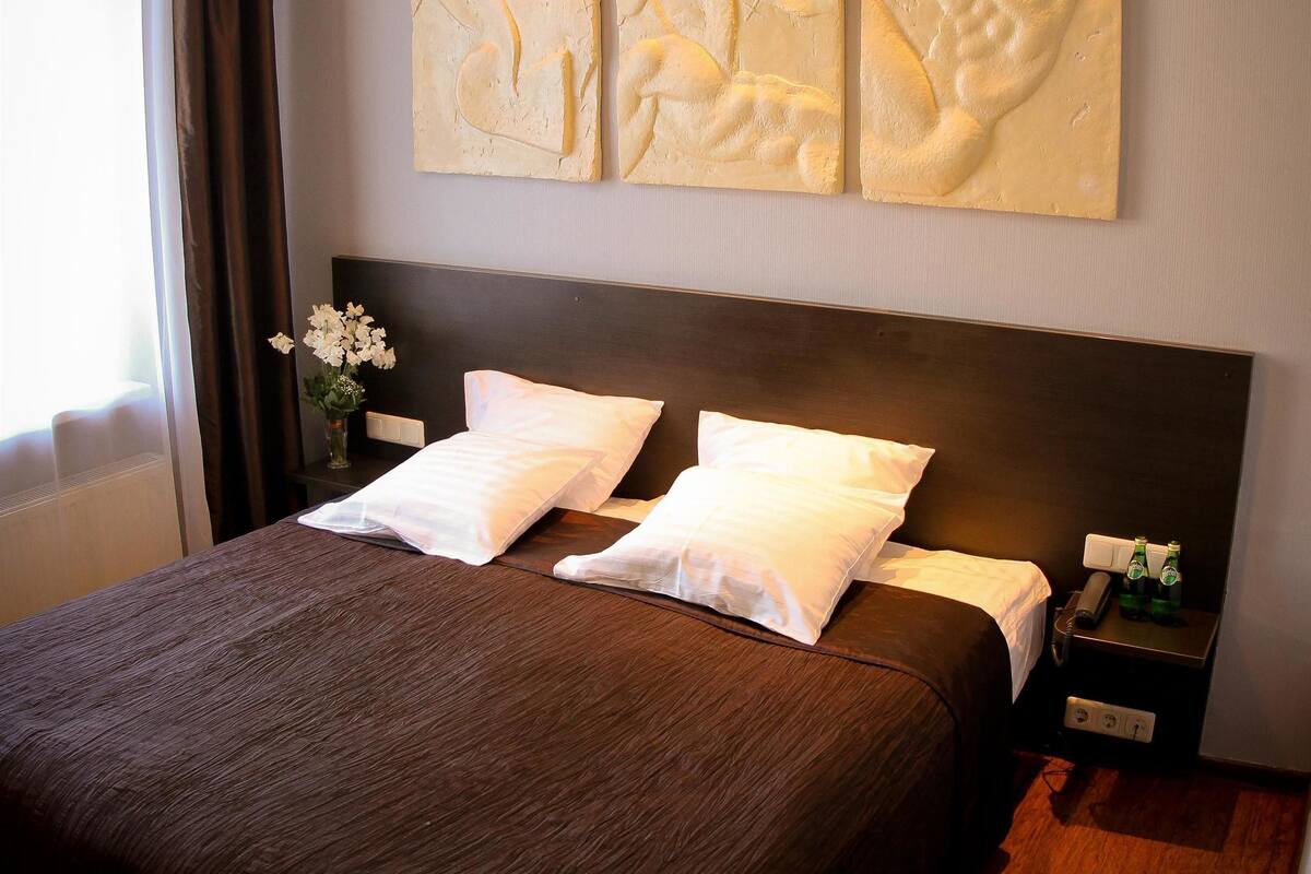 Ein Hotelzimmer mit einem großen Bett, zwei Nachttischen und Wandbildern.