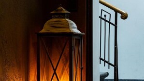 Un rincón con un farol encendido, una escalera y un suelo de baldosas.