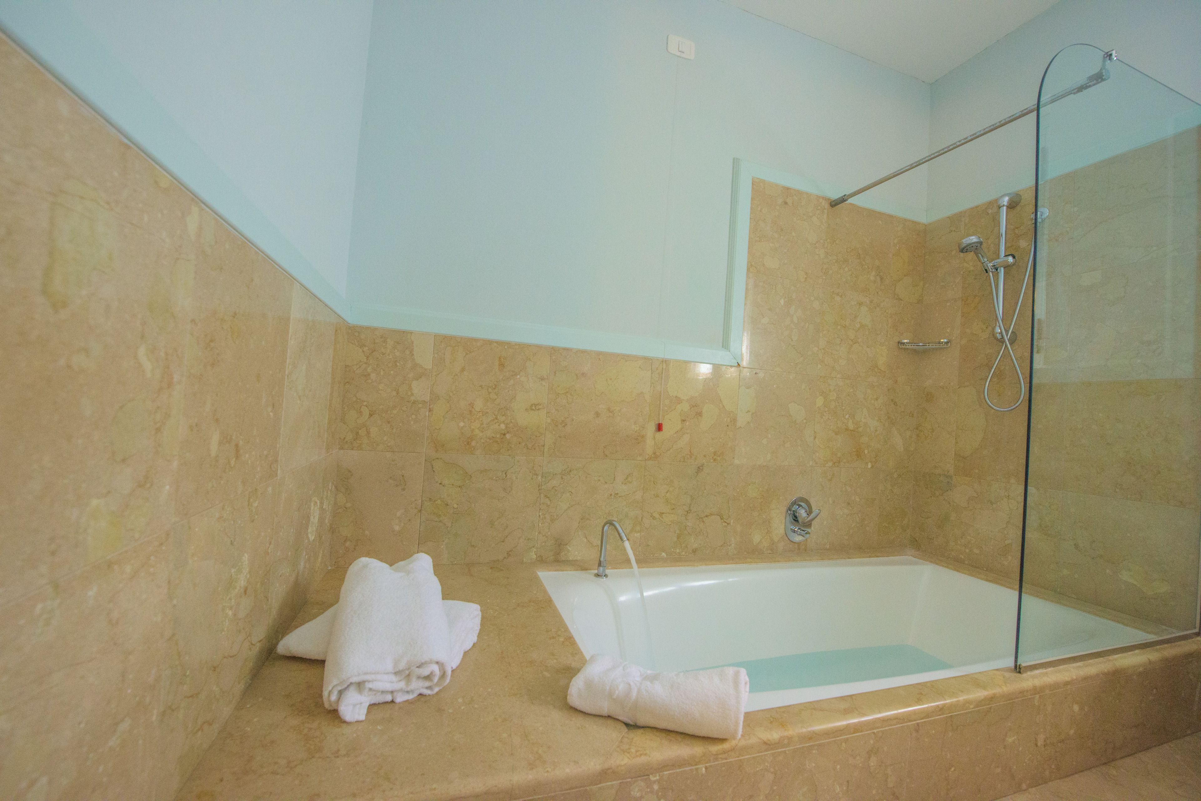 Un bagno con una vasca, un box doccia in vetro e un rivestimento in marmo.
