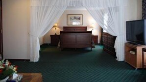 A hotel room with a bed, a TV, a dresser, and a nightstand. - Commons Inn (Halifax)