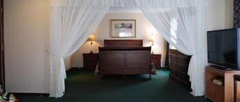 Una habitación de hotel con cama, televisión, cómoda y mesita de noche.
