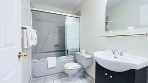 A modern bathroom with a glass shower enclosure, a white toilet, and a vanity with a sink. - Commons Inn (Halifax)