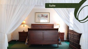 A bedroom with a bed, two bedside tables, a dresser, and a painting on the wall. - Commons Inn (Halifax)