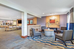 A spacious lobby with a reception desk, seating area, and a kitchen in the background.
