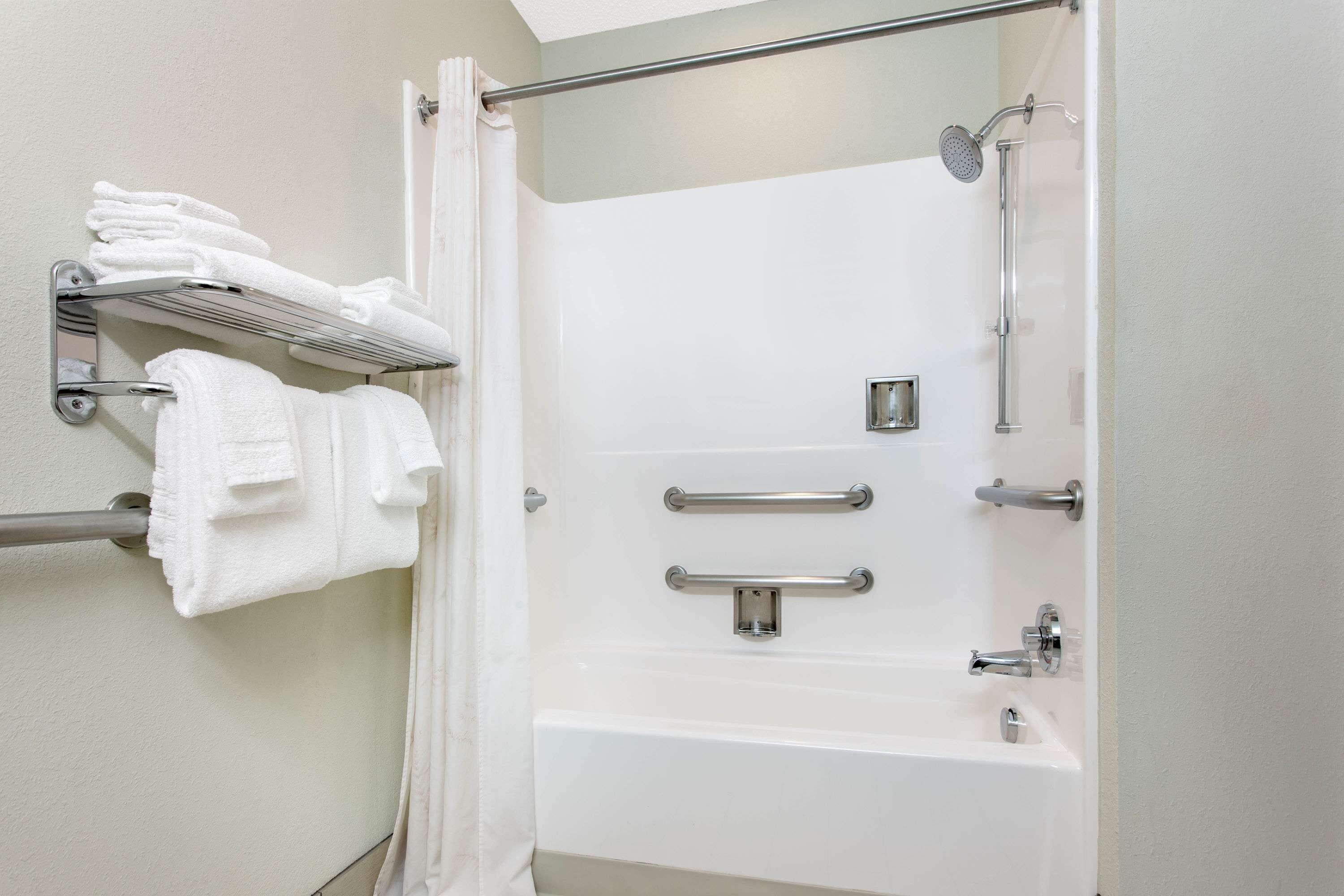 A modern bathroom with a walk-in shower, grab bars, and a towel rack.