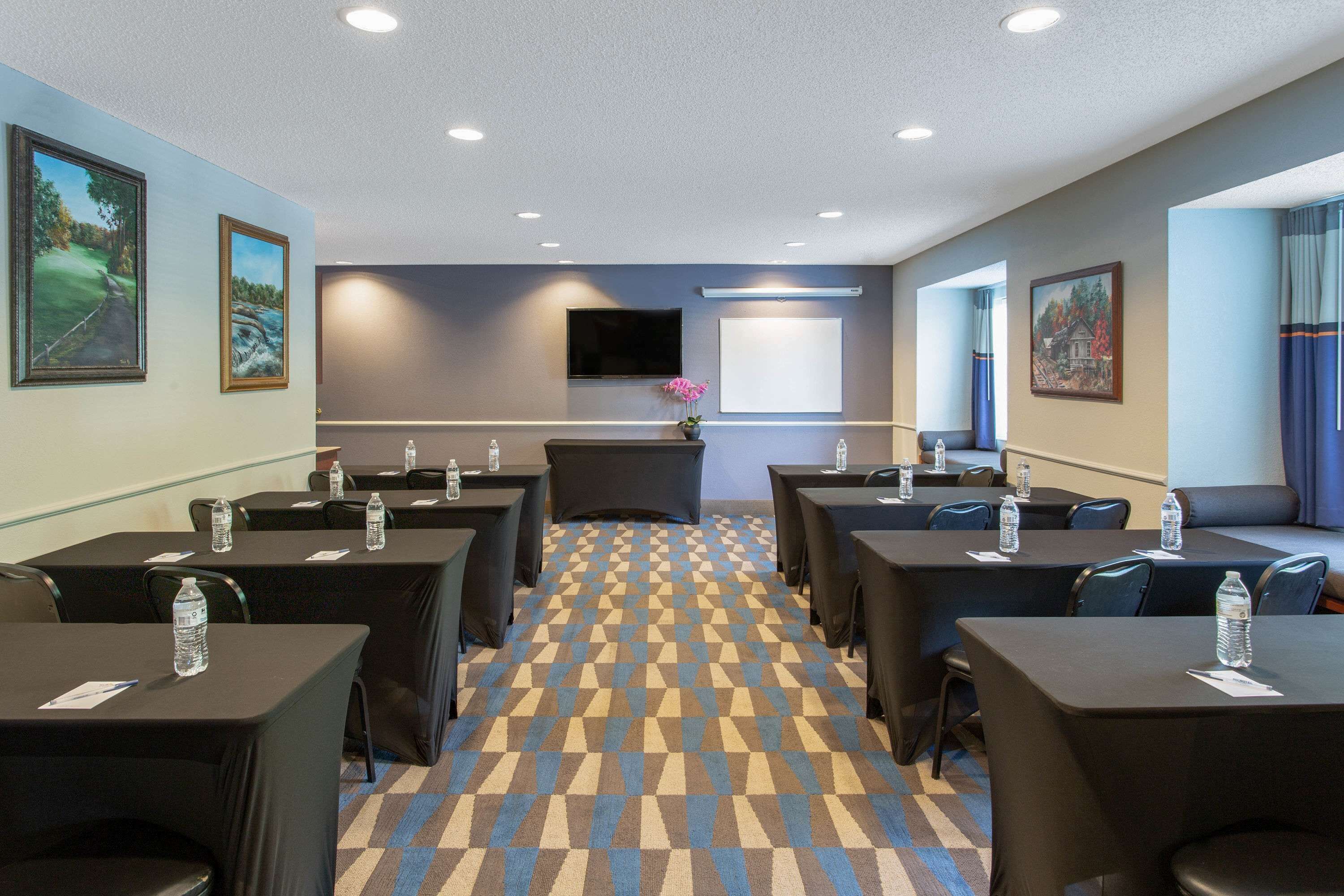 A conference room with tables, chairs, and a carpeted floor.