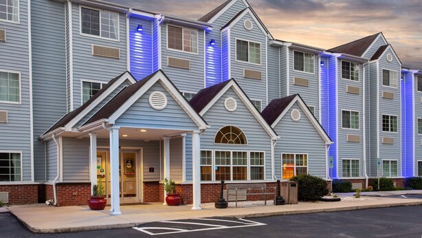 A multi-story hotel with a modern design, featuring a covered entrance and a brick facade. - Microtel Inn & Suites by Wyndham Lillington / Campbell Univ (Lillington)